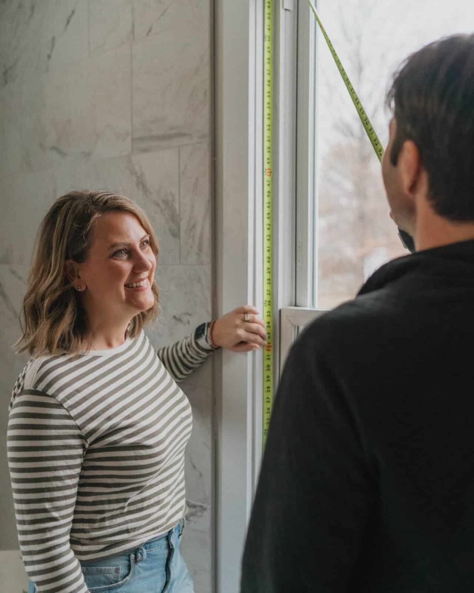 Paul and Rebecca Presson Man and woman measure a bathroom window.